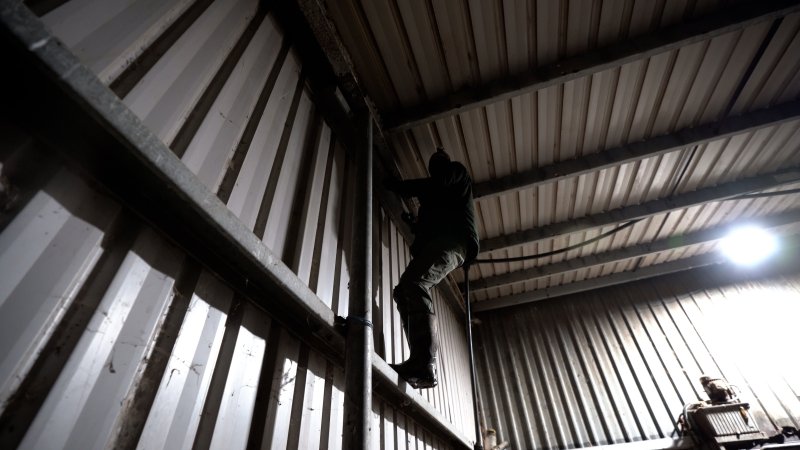 An investigator climbs a wall to look for places to install hidden cameras